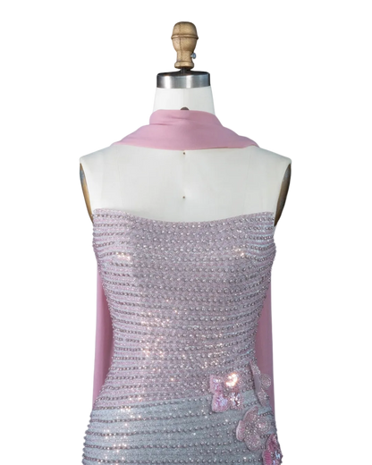 A mannequin torso wearing a pale pink draped scarf and a strapless lavender sequined dress with pink floral embellishments, shown against a light blue background. The text 'RIVIERA BOARD THE WARDA' appears in the top left corner.