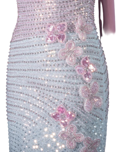 Close-up of a shimmering lavender and silver embellished dress with pink sequined flower appliqués, shown on a mannequin against a pale background.