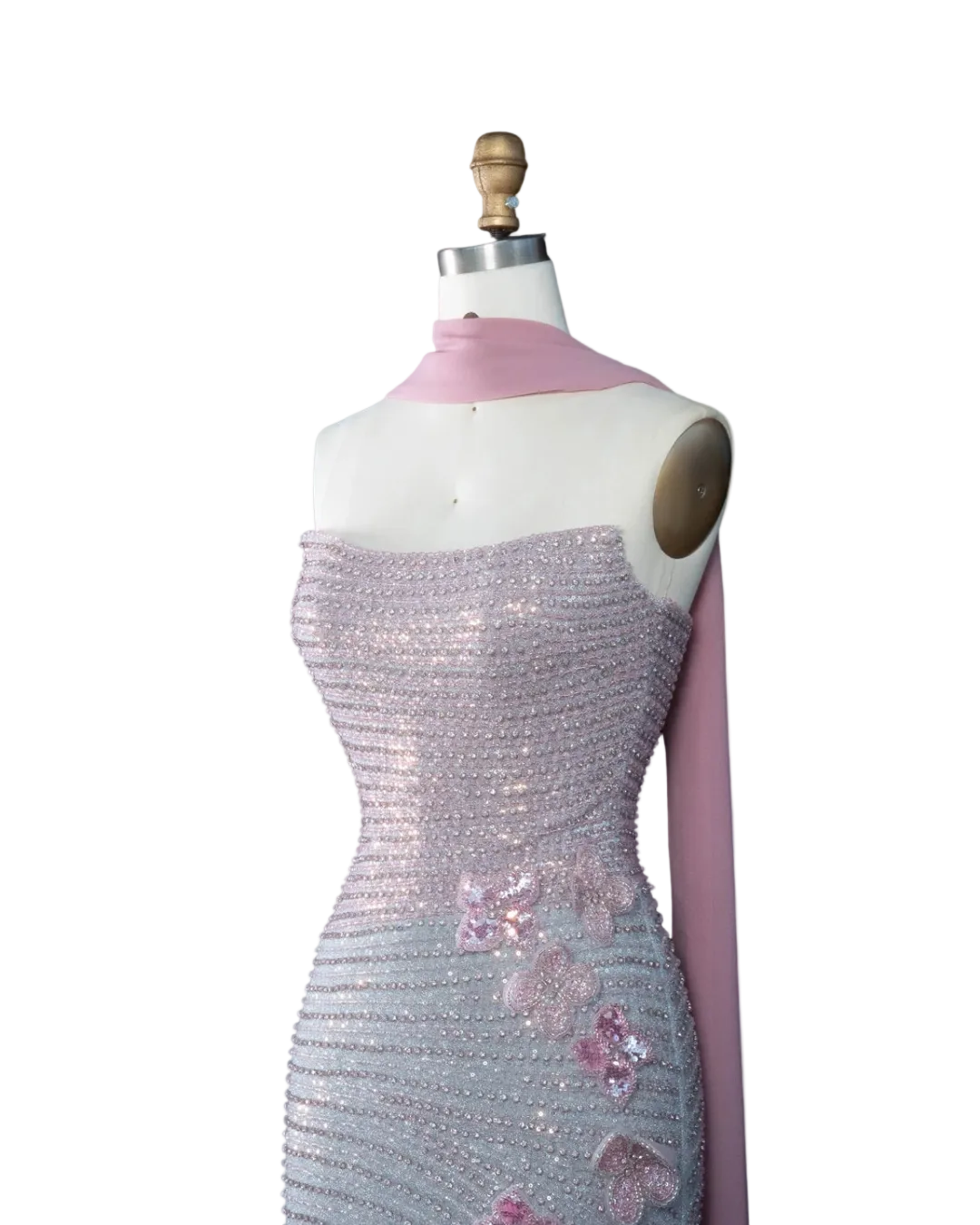 A strapless evening gown displayed on a dress form mannequin against a pale blue background. The dress is covered in shimmering silver sequins with pink floral applique and a matching pink draped scarf.