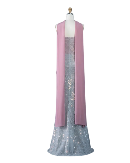 A sleeveless pink draped vest or shawl displayed on a mannequin over a sparkling silver sequined gown, shown against a pale blue background with the Riviera Board the Wanda logo in the top left corner.